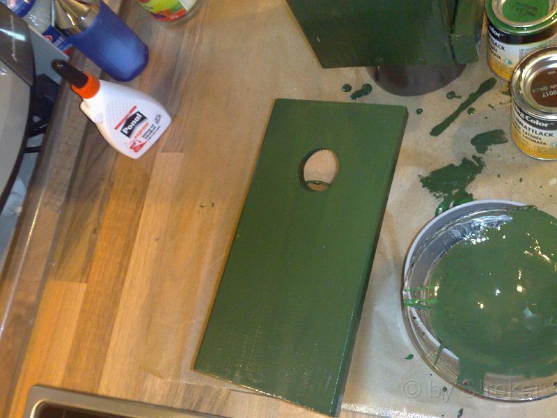 09.jpg - Die Tür des Vogelhauses.Evtl. beim Cachen nicht zu sehen: Die Tür (und auch das restliche Haus) besitzt eine Abdichtung aus Silikon, umFeuchtigkeit und den kleinen Krabbeltieren das Leben so schwer, wie nur möglich zu machen.Das ehemalige Einflugloch ist von Innen mit Makrolon® verschlossen worden.Zunächst wurde von Innen eine Spigelfolie aufgebracht, die ein Ablesen von Außen verhindern sollte.Allerdings gab es einen chemischen "Unfall" zwischen der Spigelfolie und dem Makrolon und die Folie löste sichwieder ab. Ich suche immer noch nach einer besseren Lösung als jetzt, wo alles so "nackig" ist.